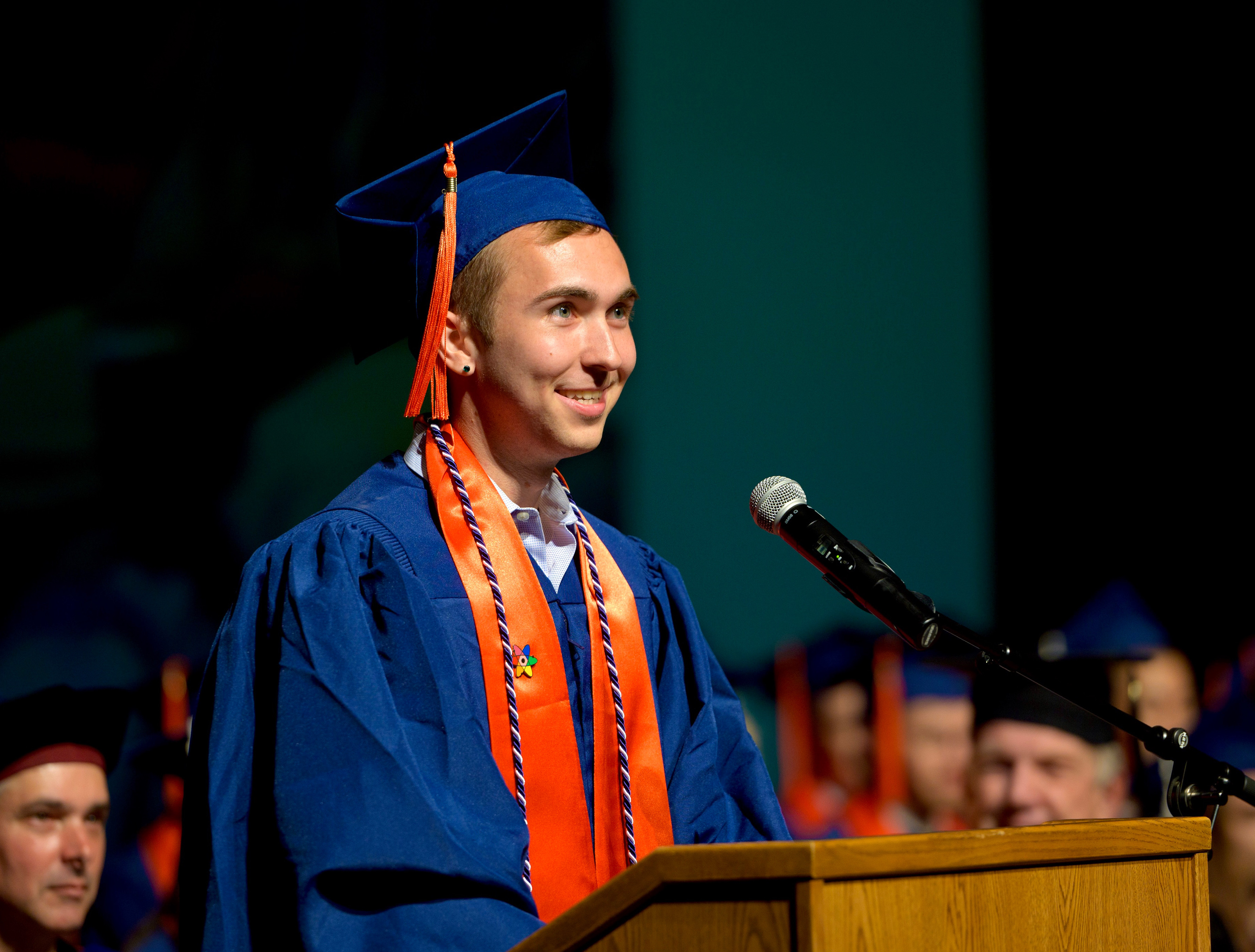 Nathan standing at a podium in cap and gown at graduation.